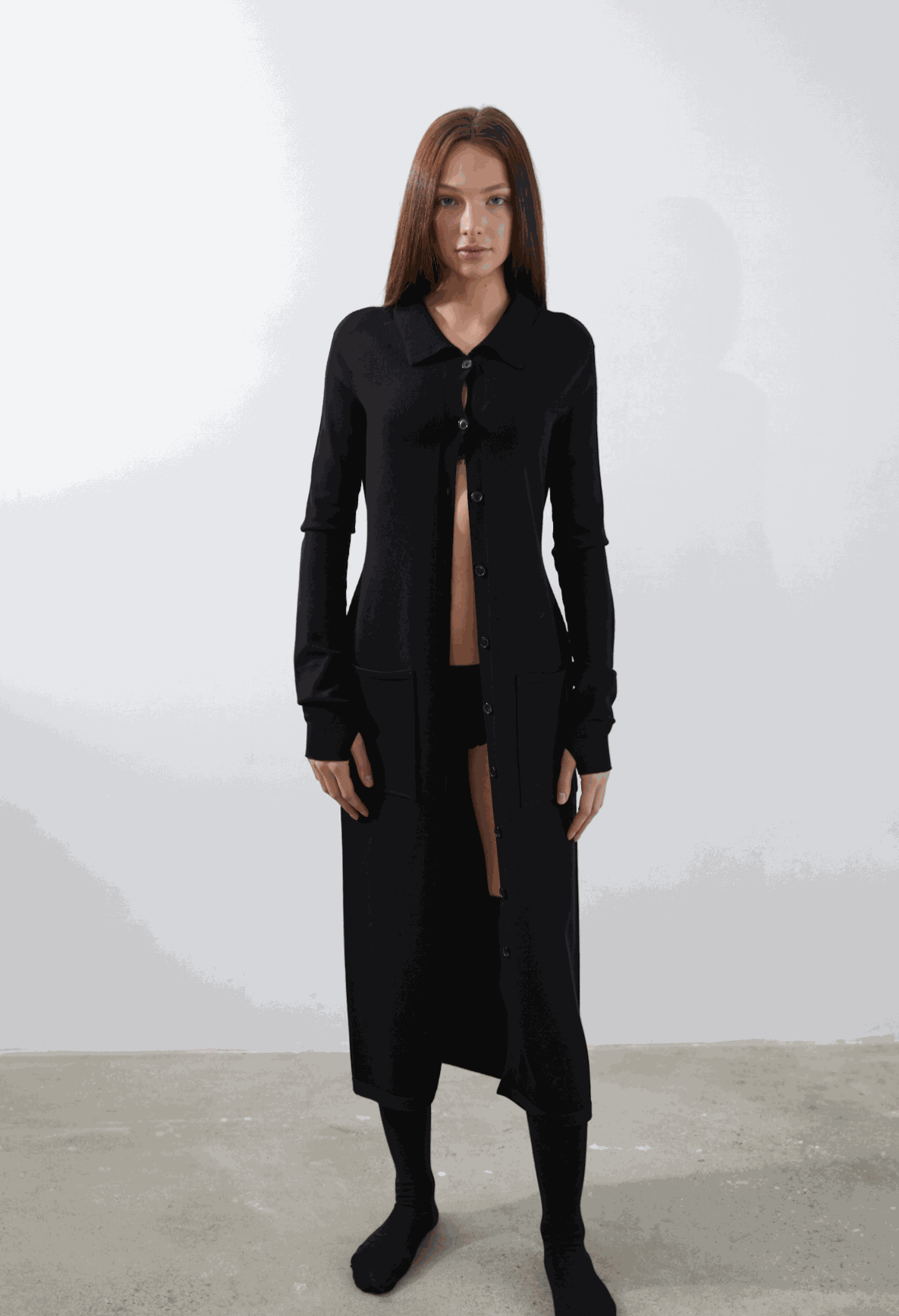 Camael Cardigan in black, featuring long sleeves, button-up design, structured pockets, and cuffed sleeves with thumbholes.