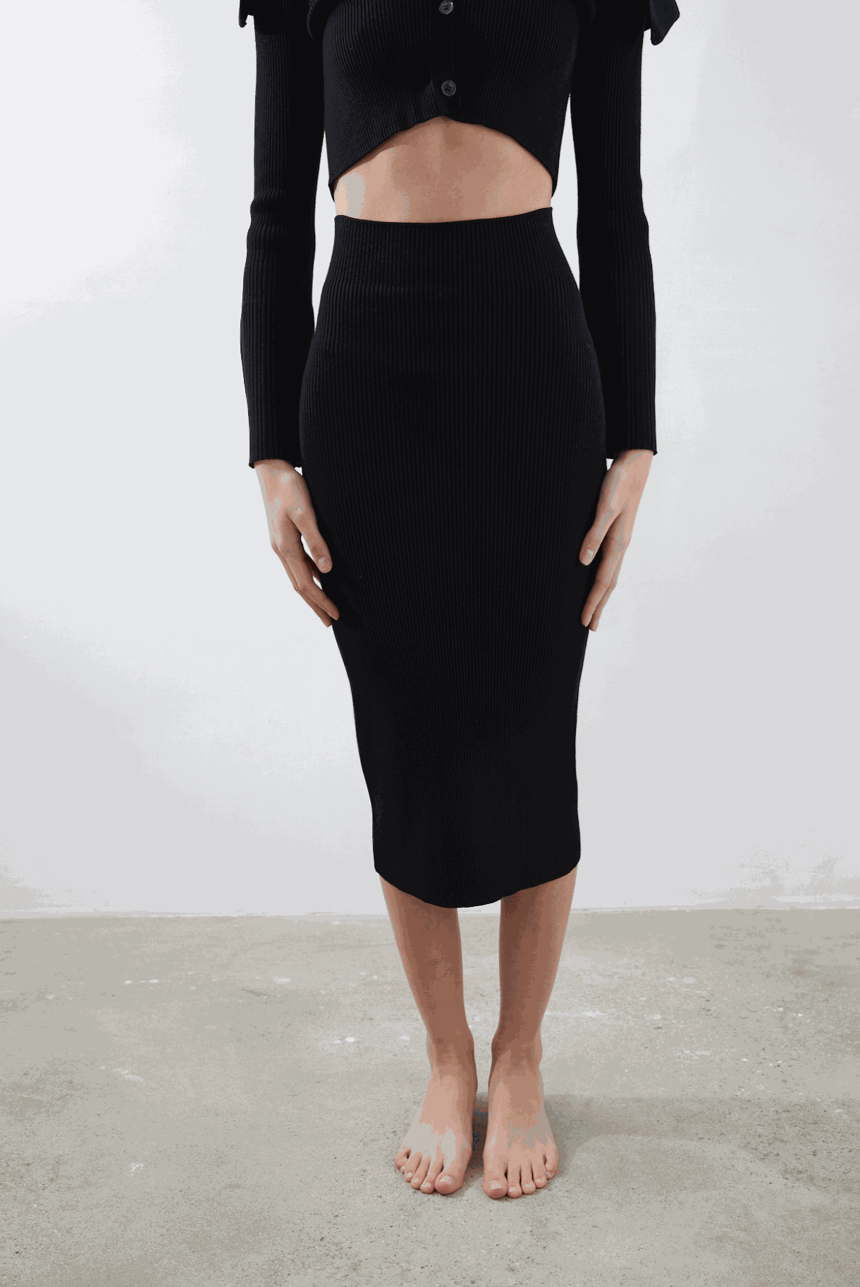 Juno Pencil Skirt in black, eco-friendly, shin-length design, worn by model showing seamless contour fit.