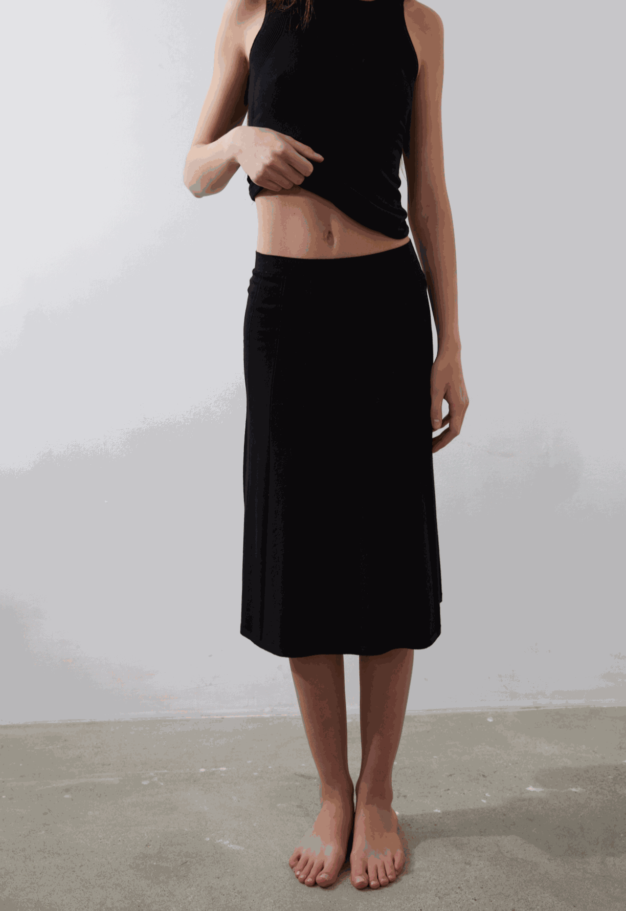 Vega Skirt in black with subtle pleated texture and sleek waist fit.